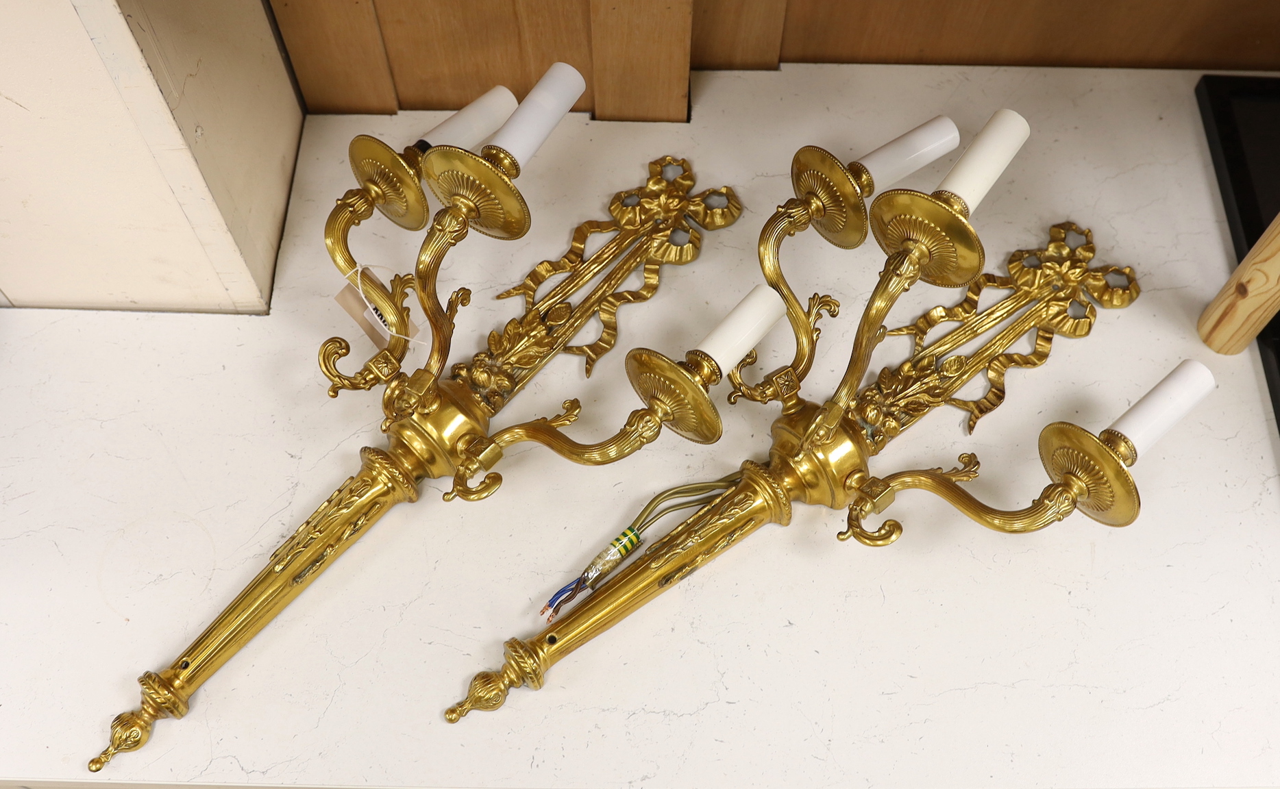 A pair of gilt metal three branch wall lights, 61cm tall